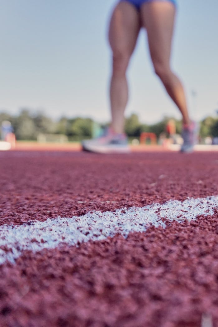 Closeup view of athlete's legs standing on outdoor track, perfect for sports-related themes.