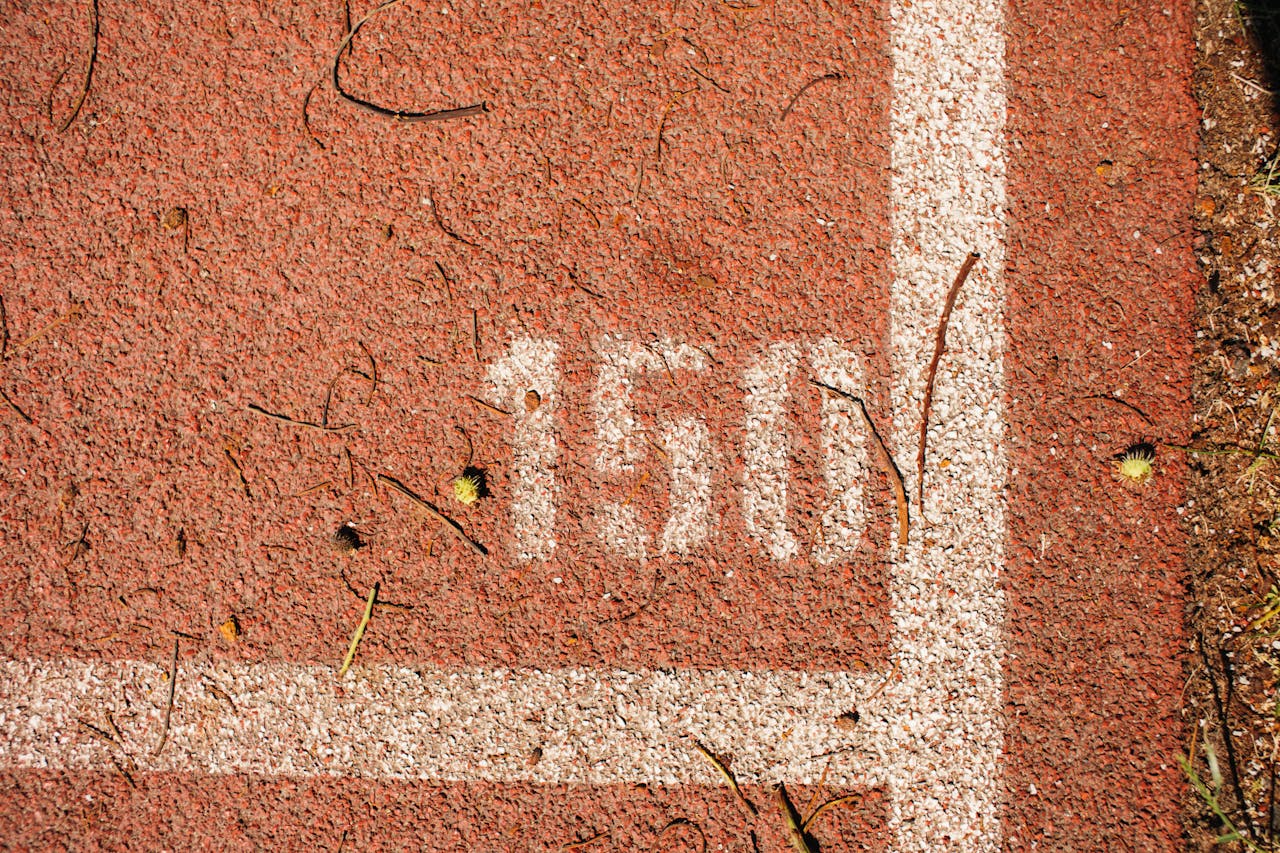 Close-up of a running track showing the number 150 marked on red surface with white lines.